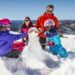 Family building a snowman at Perisher Ski Village in the Snowy Mountains after a day of skiing.