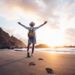 Young man arms outstretched by the sea at sunrise enjoying freedom and life, people travel wellbeing concept